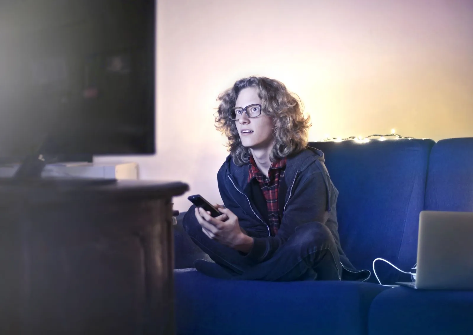 Utilisateur vérifiant son smartphone devant une télévision